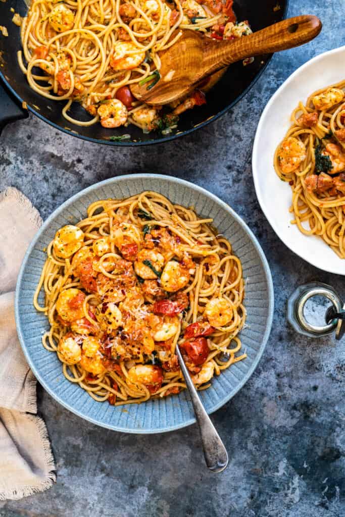 Two servings of prawn pasta in bowls plus a pan on the side