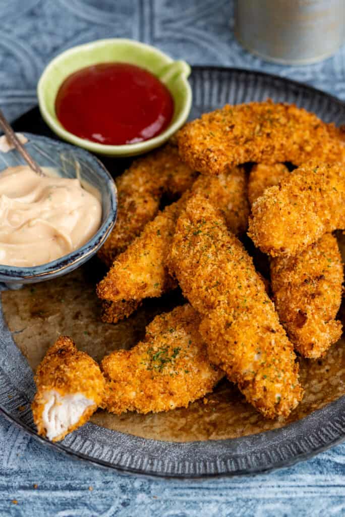 plate of chicken fingers with dipping sauces on the side