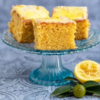 Three slices of lemon drizzle traybake on a small cake stand