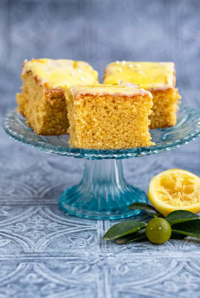 Three pieces of lemon drizzle traybake on a small cake stand