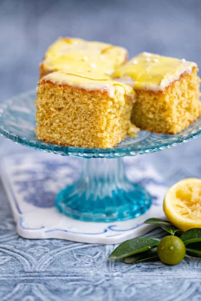 Lemon drizzle squares with glaze on cake stand