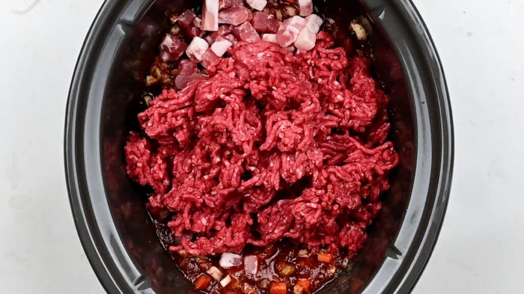 ground beef in a slow cooker in preparation for meat sauce