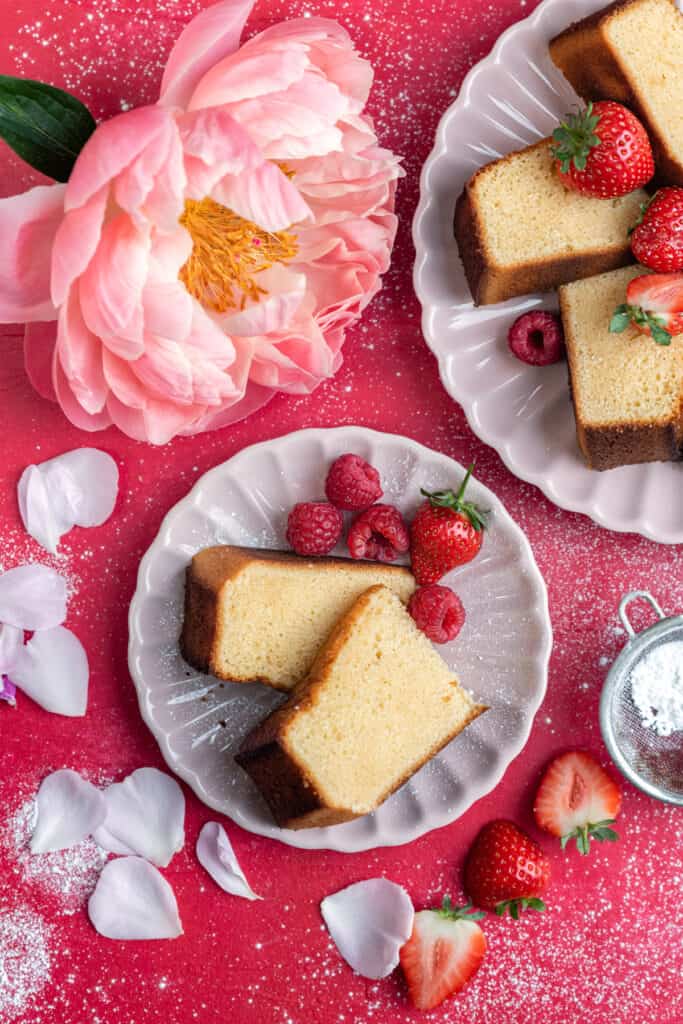 Vanilla pound cake with condensed milk sliced on plates against pink backdrop