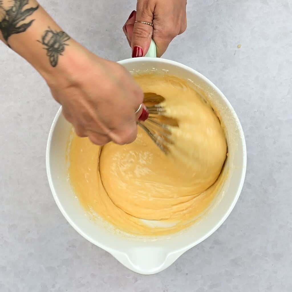 stirring condensed milk cake ingredients in a bowl