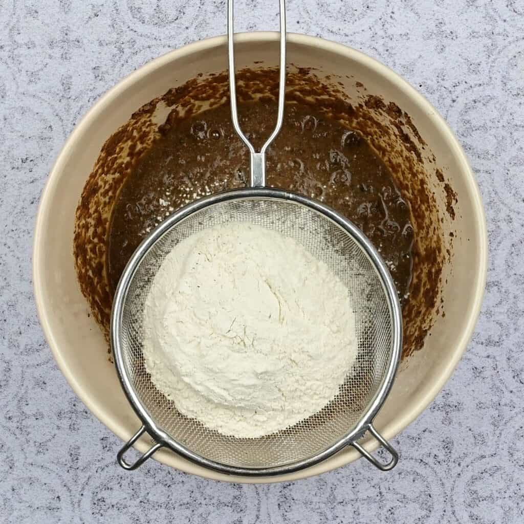 Sifting flour into batter in a bowl