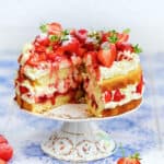 Strawberry shortcake cake on a cake stand with slice cut out