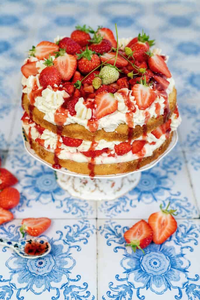 Vanilla strawberry cake on a stand decorated with fresh strawberries