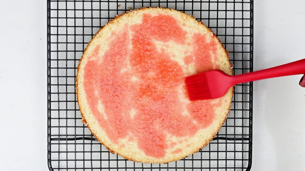 brushing sponge cake with strawberry syrup