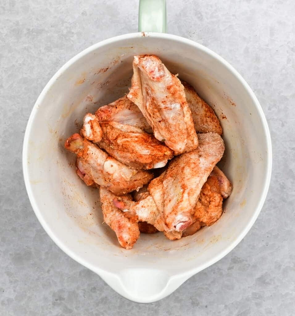 Chicken wings in a bowl with seasoning