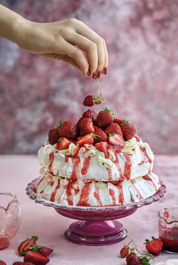decorating meringue cake with fresh strawberries