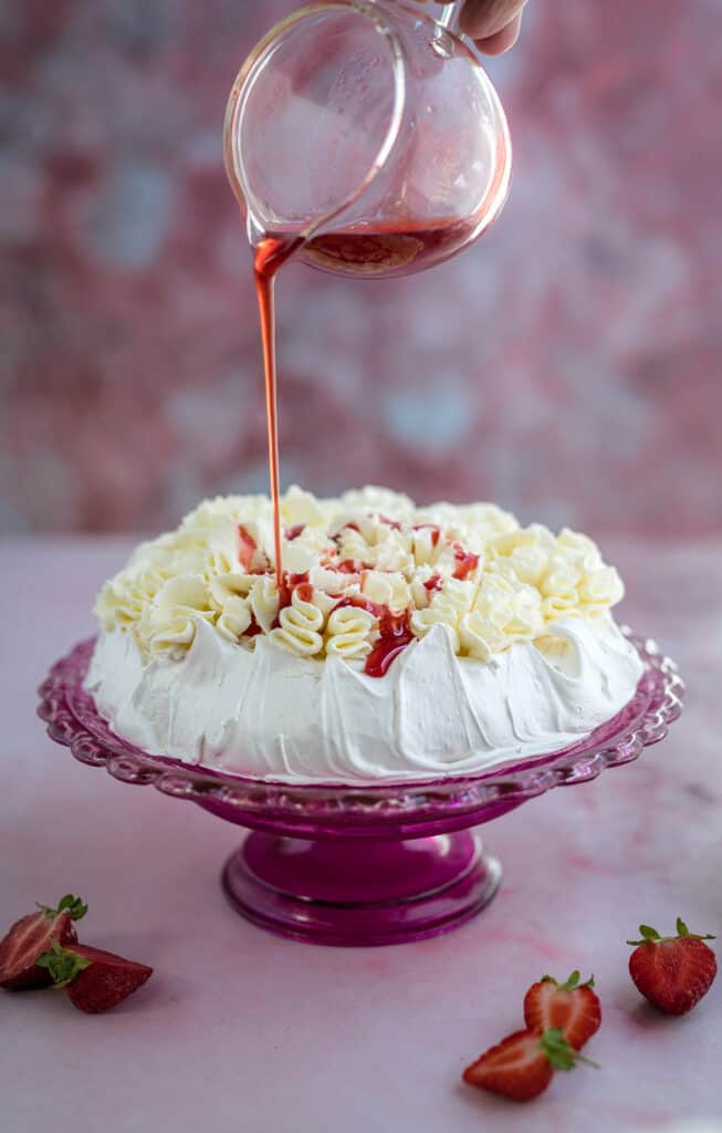 drizzling strawberry syrup over meringue cake