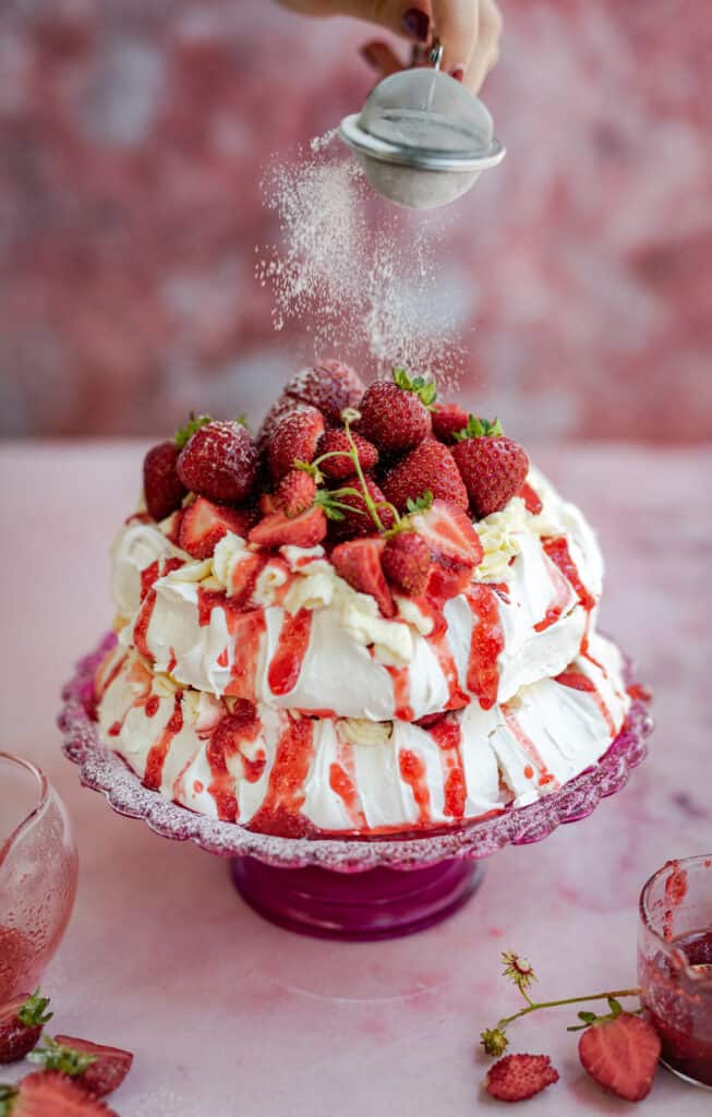 Meringue cake with whipped cream and fresh strawberries on a cake stand