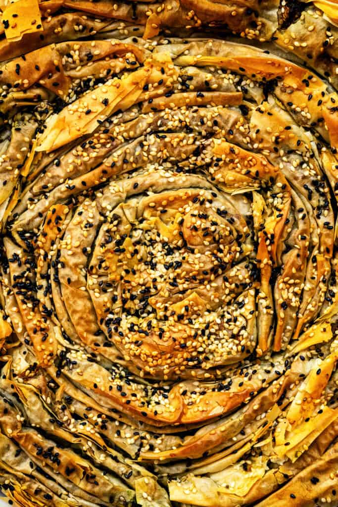 close up on spanakopita soufra, a ruffled spinach and feta pie topped with sesame seeds