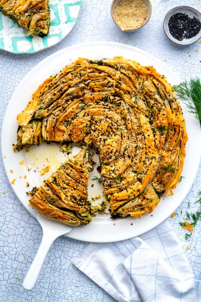 Photo of Spinach and Feta Pie – Spiral Spanakopita – on a platter with slices cut out