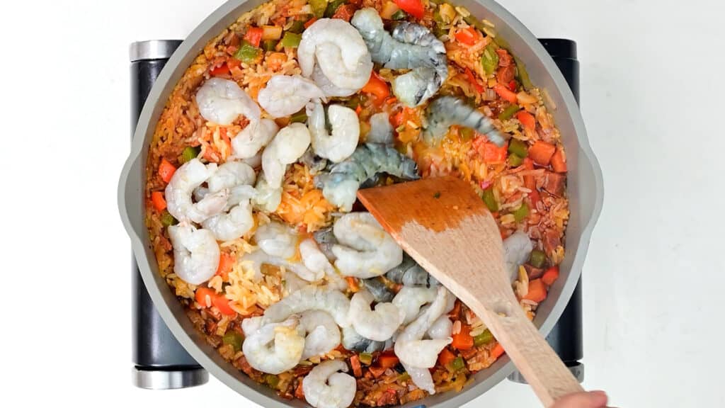 stirring raw shrimp into a pot of Cajun rice