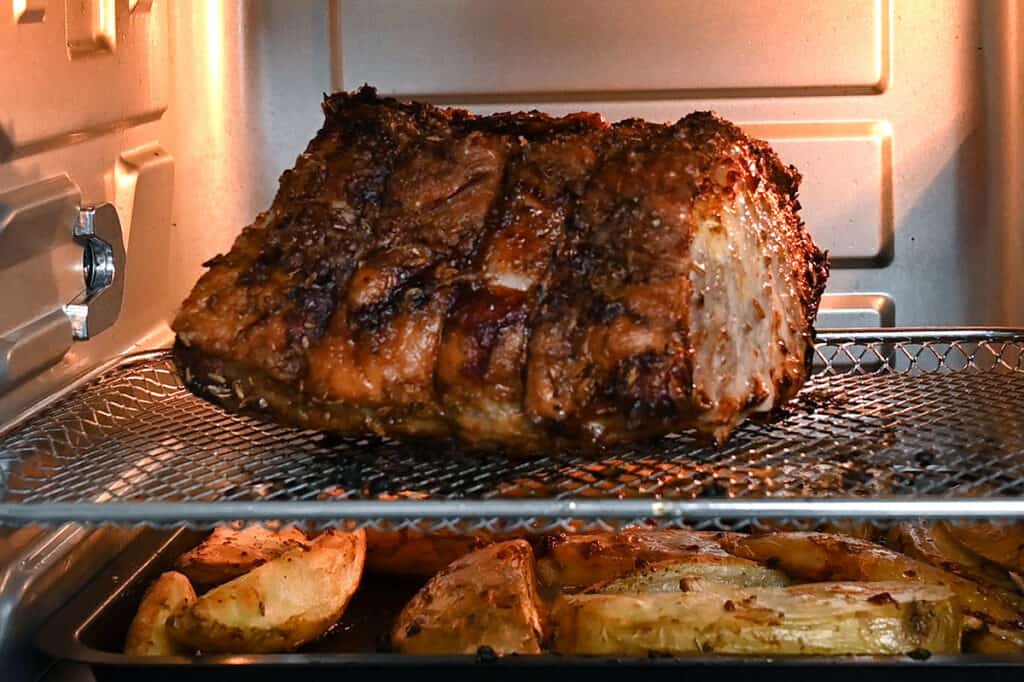 Roast pork in an air fryer with potato wedges underneath