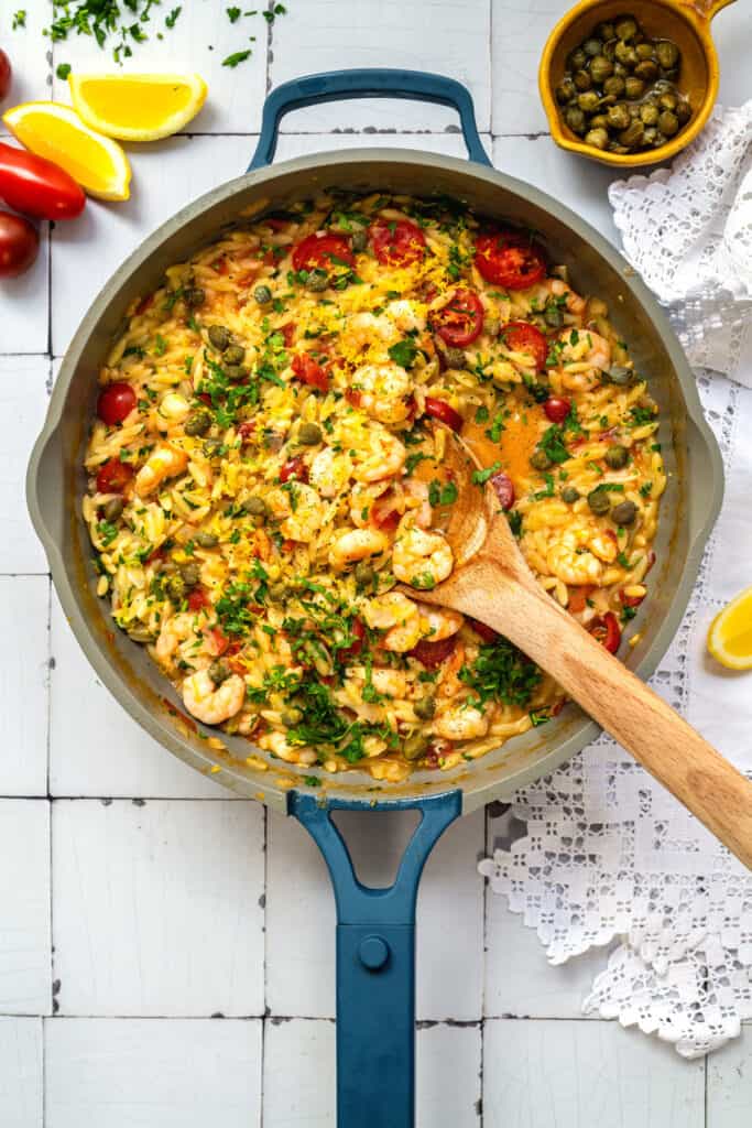 Orzo with shrimp, tomatoes, capers, parsley in a pan