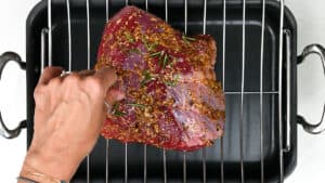 Seasoned beef joint set on a rack over a roasting pan