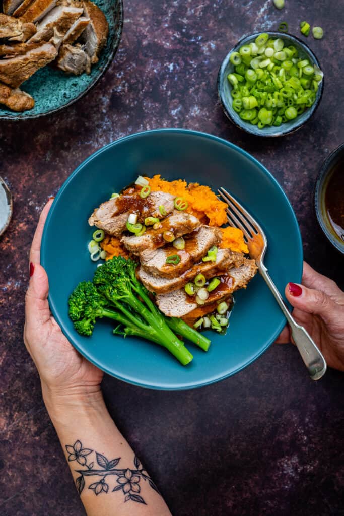 Sliced pork fillet served in a bowl with sweet potato mash and steamed broccoli spears