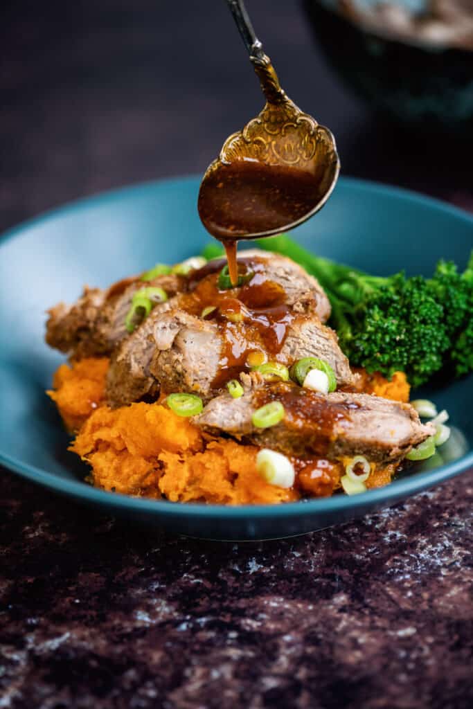 Slow cooker pork tenderloin served over sweet potato mash and drizzled with sweet spicy sauce