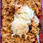close up on plum and apple crumble topped with vanilla ice cream