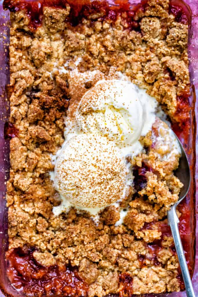 close up on plum and apple crumble topped with vanilla ice cream