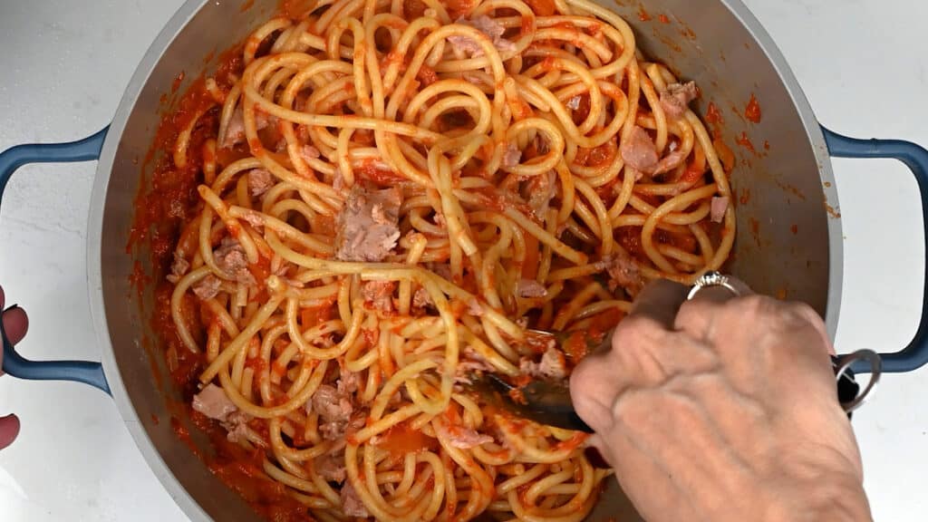 tossing pasta with tomato sauce