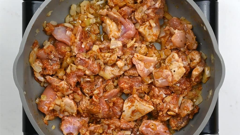 pan containing onion, garlic, chicken and sundried tomatoes