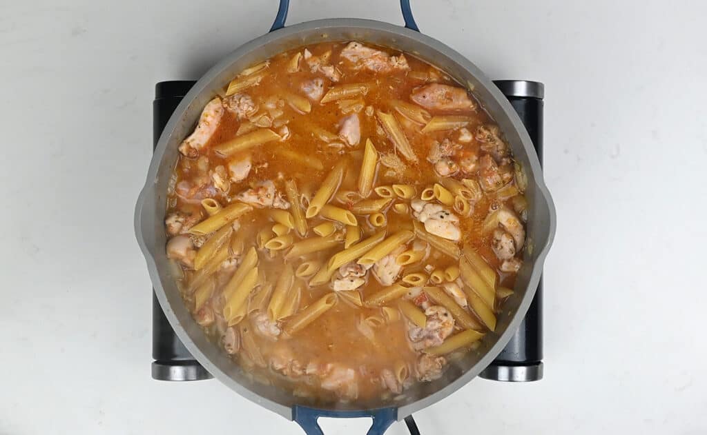 tuscan chicken pasta cooking in a large pan