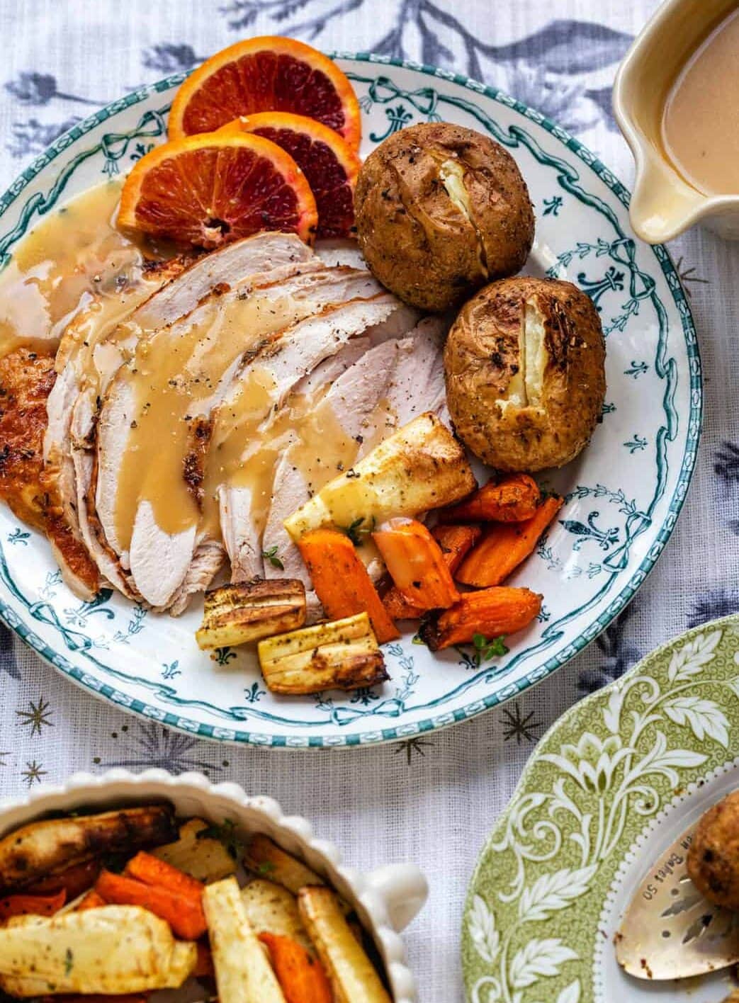 sliced turkey breast on a plate with gravy and side dishes