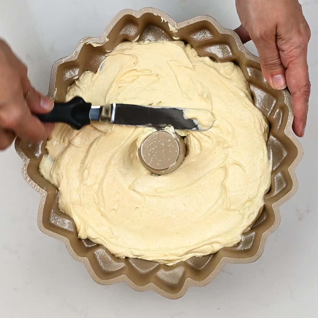 leveling lemon cake batter in a bundt pan