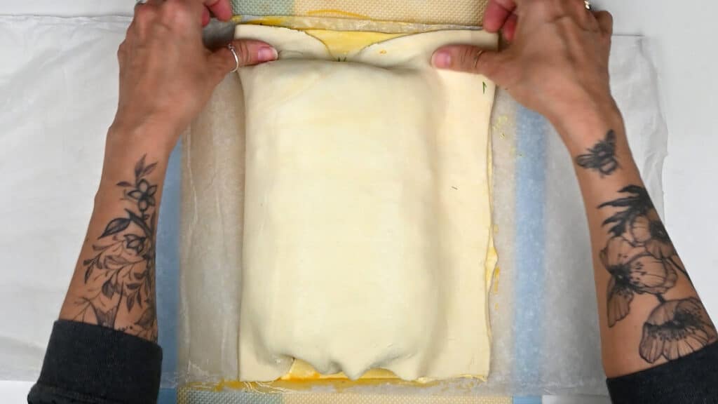 pressing puff pastry to seal salmon parcel