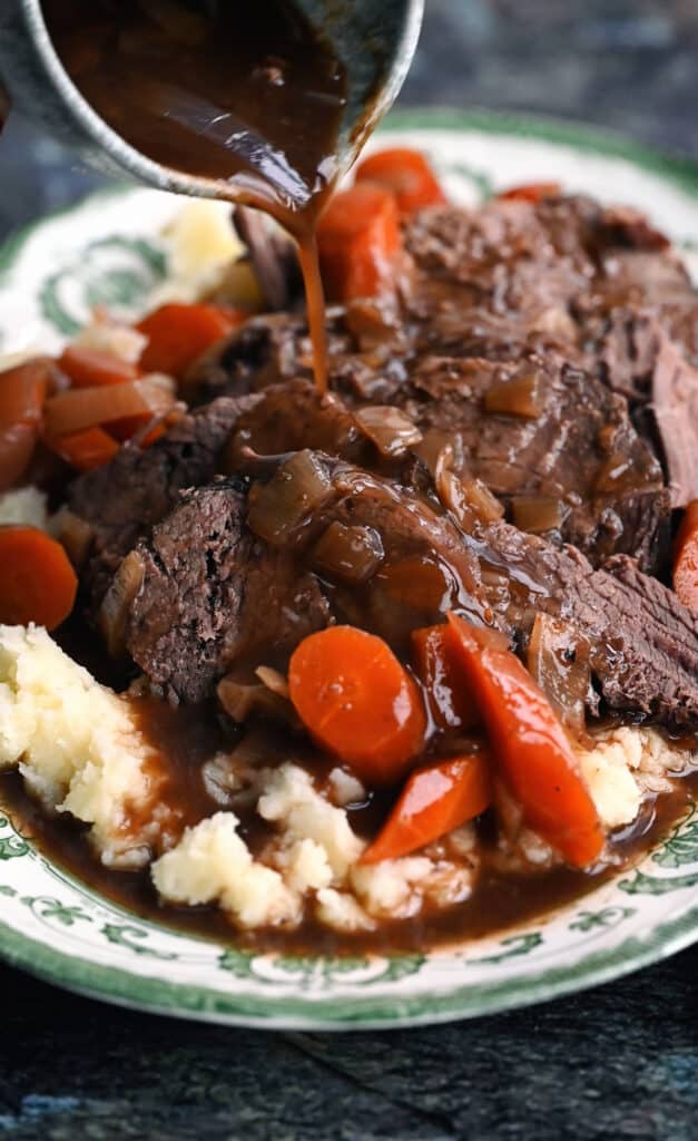 Pouring gravy over slow cooker deer on a plated