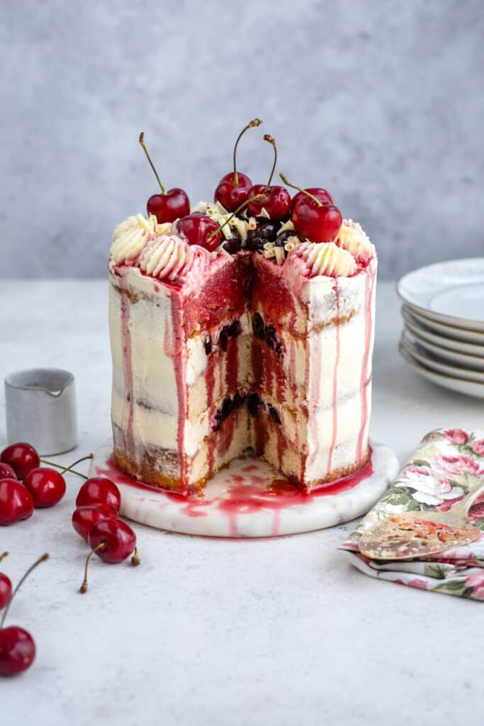 White forest gateau on a plate with slice cut to show the layers