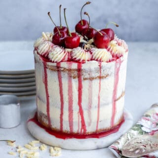 White forest cake decorated with fresh cherries and white chocolate frosting