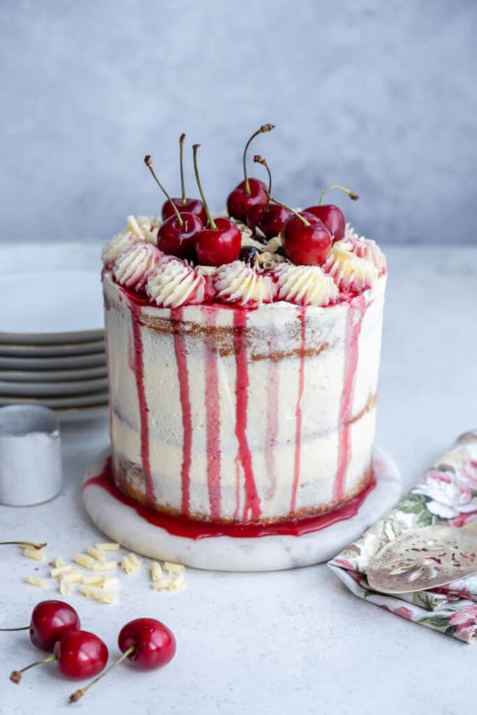White forest cake decorated with fresh cherries and white chocolate frosting