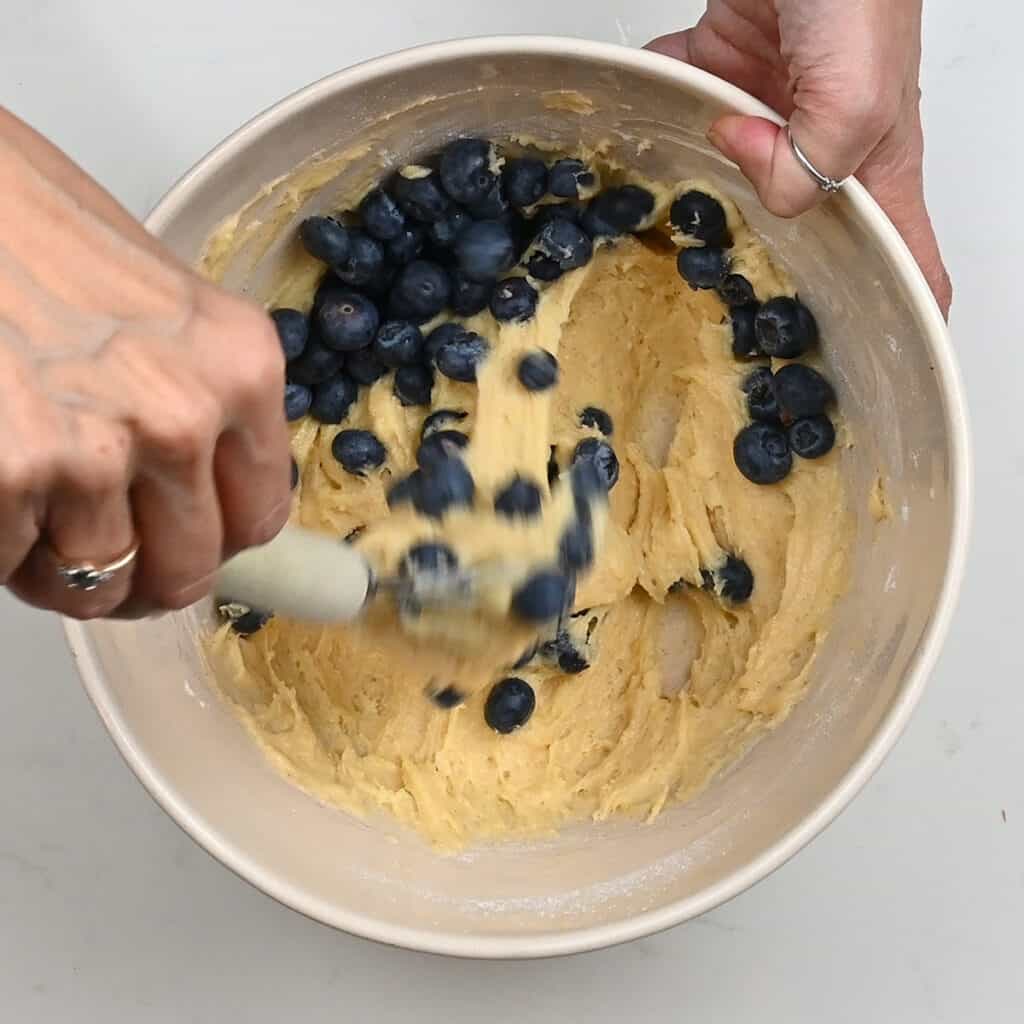 folding fresh blueberries into muffin batter