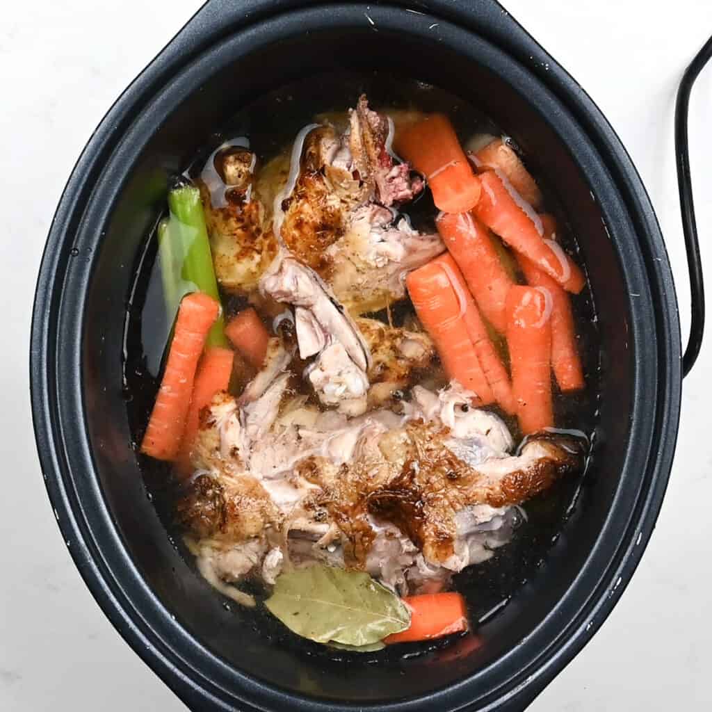 chicken carcass, carrots and celery in a slow cooker