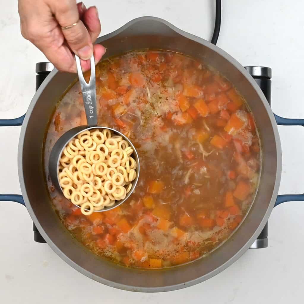 Adding pasta to pot of chicken soup