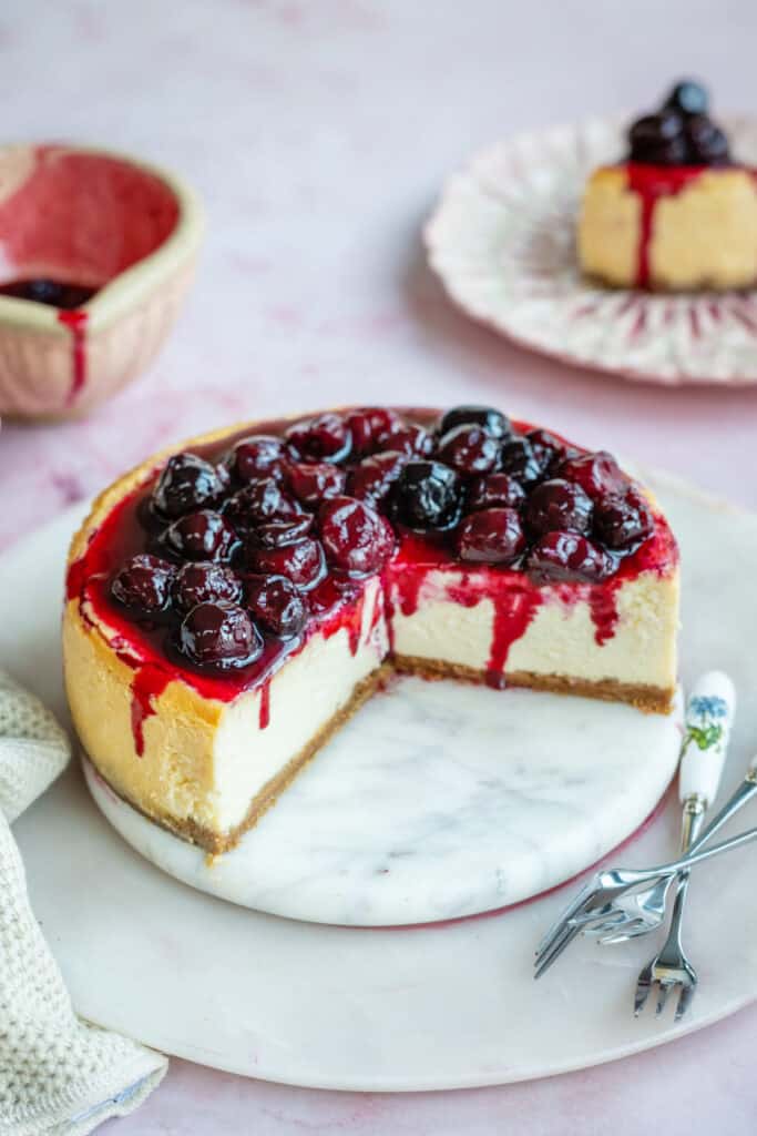 Sliced baked cheesecake topped with cherries