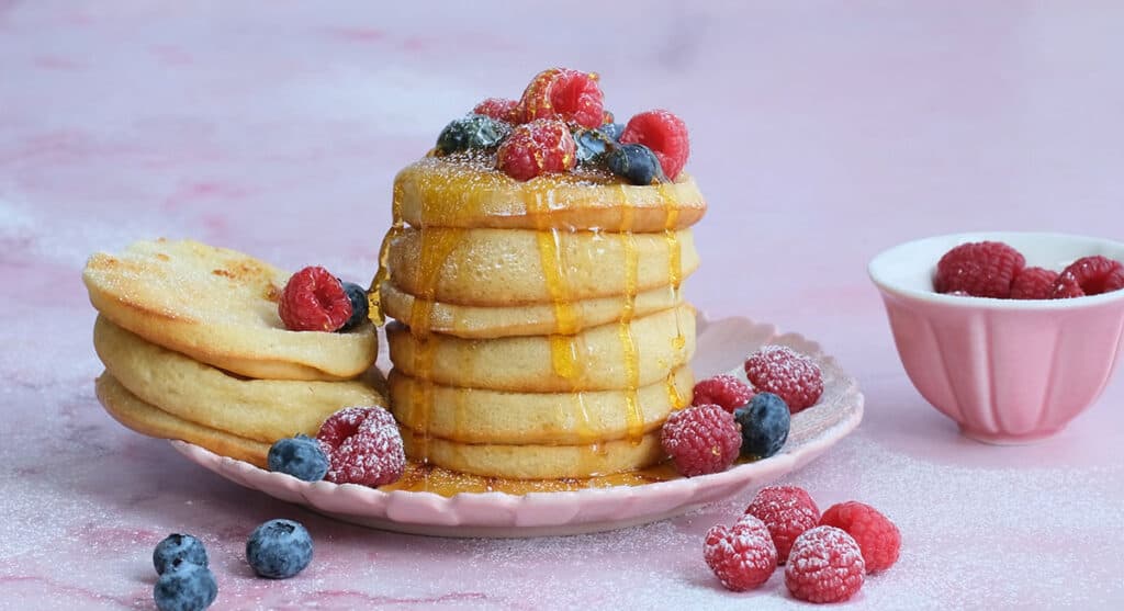 stack of buttermilk pancakes with syrup and berries