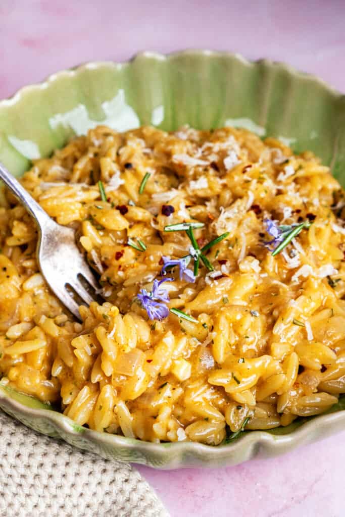 bowl of orzo cooked in rosemary browned butter garnisehd with parmesan, chili flakes and rosemary