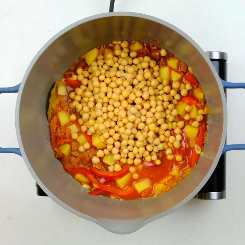 adding chickpeas to stew in a pot