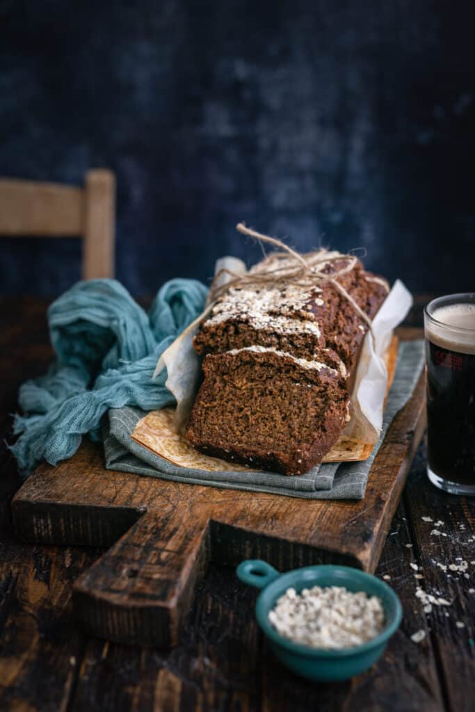 Irish Guinness bread, slice cut, on a wooden board with glass of Guinness on the side