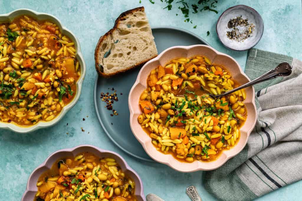 three bowls of Vegetable Orzo soup with slice of bread on the side