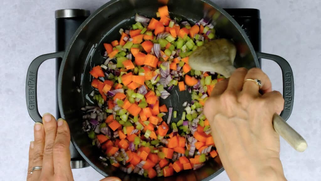 cooking onions, celery and carrots in a pot