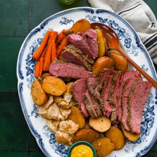 Sliced corned beef and cabbage with vegetables on a large platter