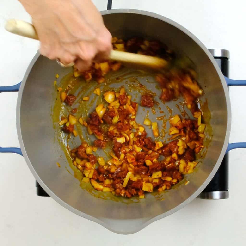 pan frying chorizo and onion in a pot