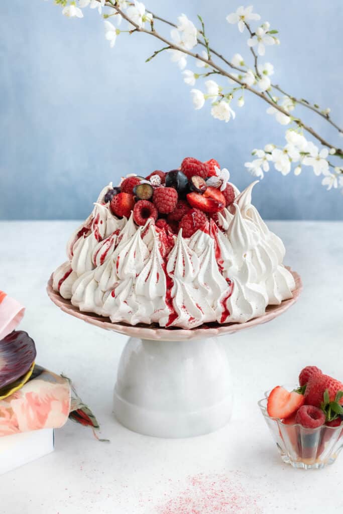 Air Fryer Pavlova filled with cream and fresh berries on a stand