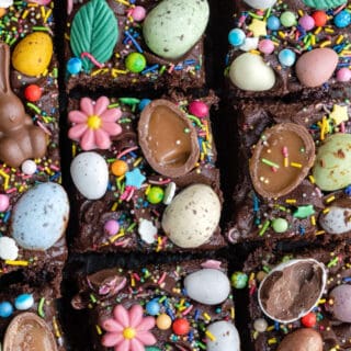 Easter traybake cake decorated with mini eggs and Easter candy, sliced
